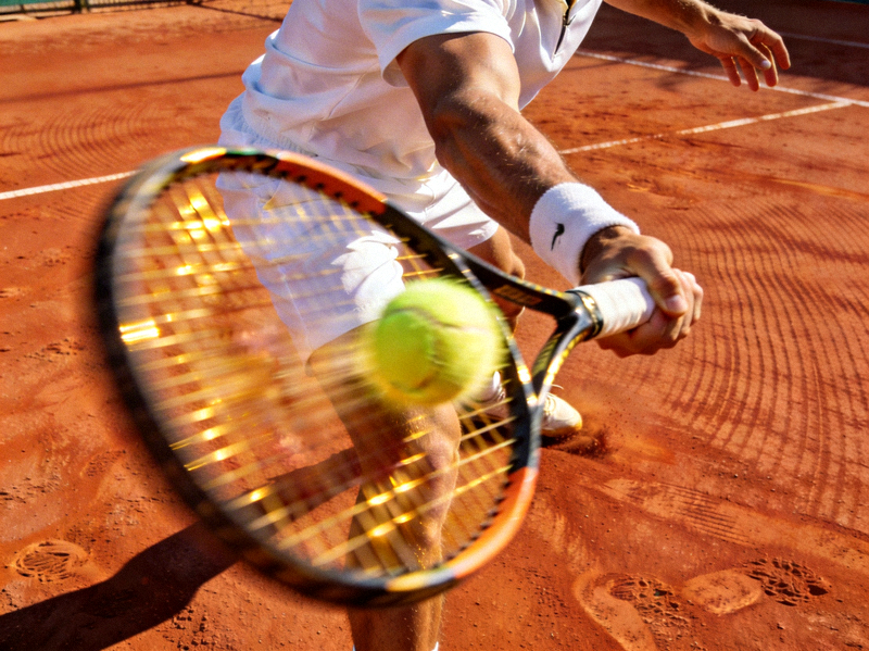 网球运动员在红土场上奋力挥拍击球的瞬间